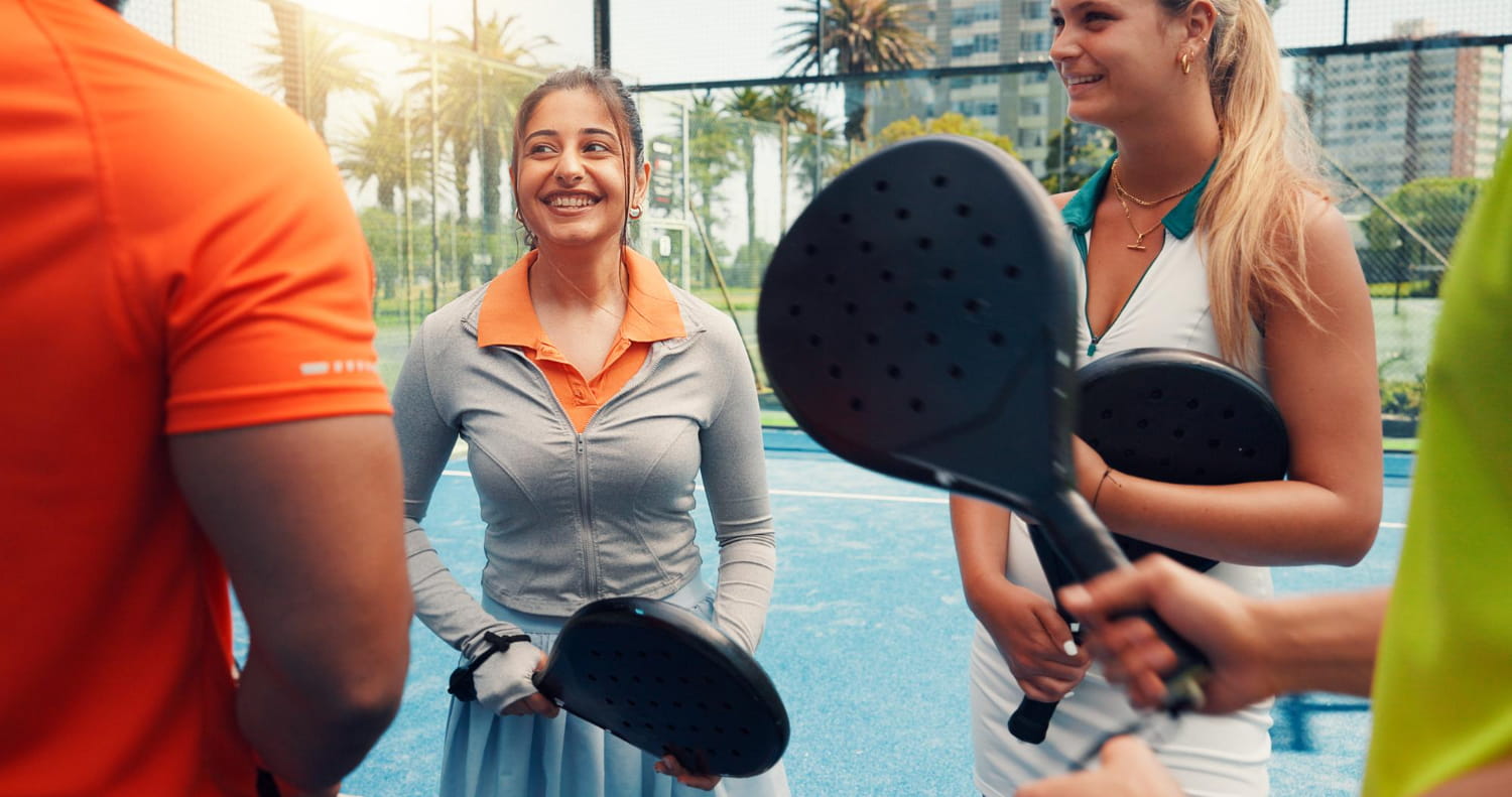 Group of padel players smiling and holding padel rackets on a blue outdoor court, similar to padel tournament Cyprus settings