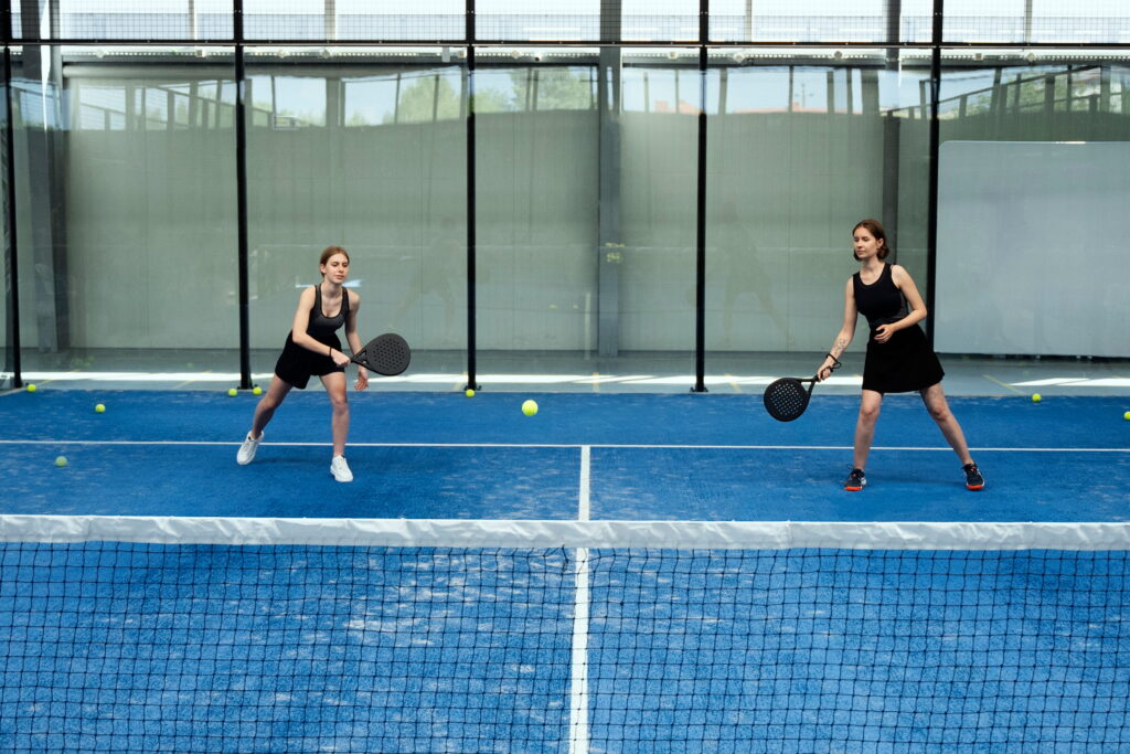 Two women playing padel on a blue indoor court at a padel club in Nicosia
