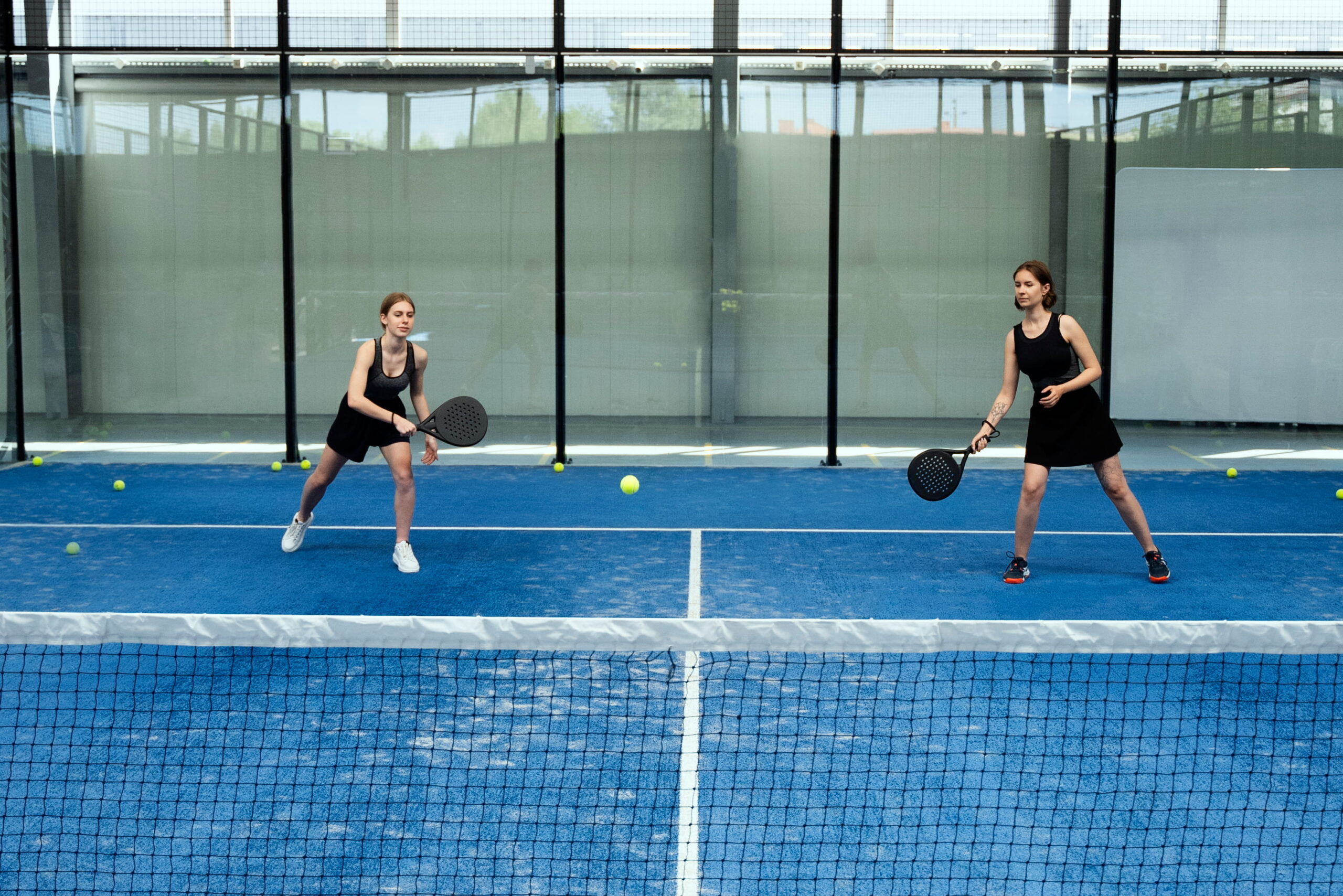 Two women playing padel on a blue indoor court at a padel club in Nicosia